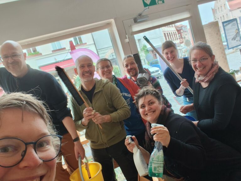 Eine Gruppe Freiwillige halten Putzutensilien in den Händen